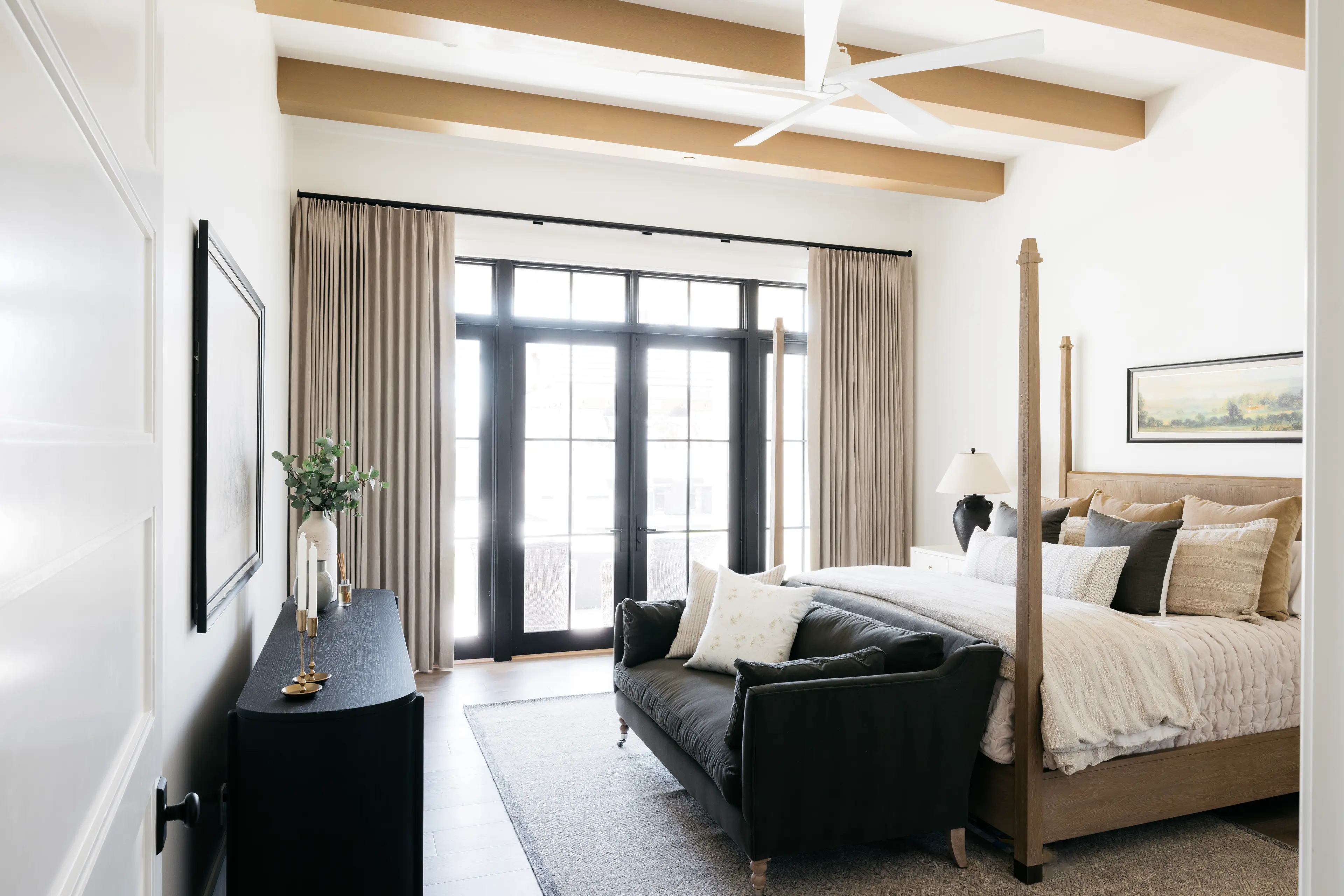 A light-filled bedroom with natural wood beams and layered neutral linens